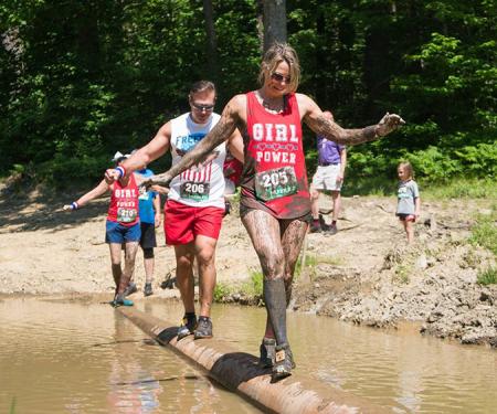 Participants balancing on a log at Holiday Valley's Mudslide mud run event